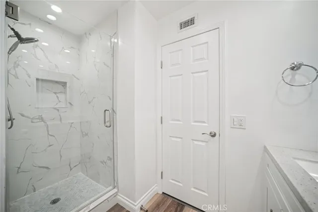 a view of empty room with wooden floor and fan