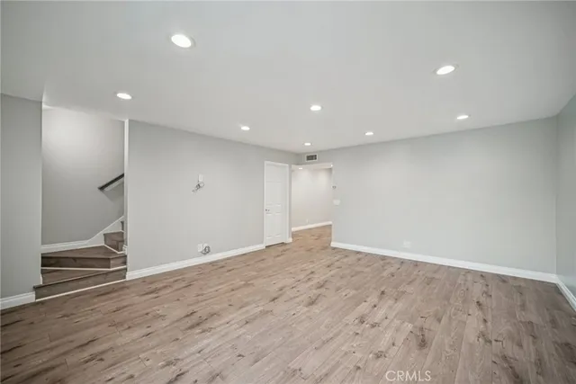 an empty room with wooden floor and entrance to ceiling window