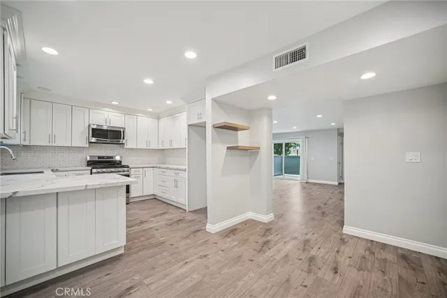 a view of kitchen with granite countertop stainless steel appliances refrigerator sink and cabinets
