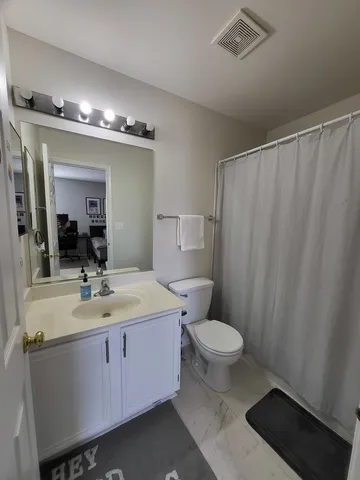 a bathroom with a sink a toilet a mirror and shower