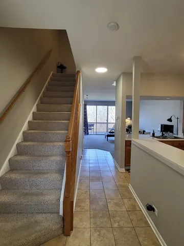 a hallway with stairs and a view of living room