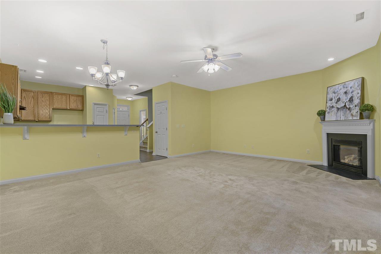 8235 Martello Lane Raleigh, NC 27613 - Photo 5 of 14 an empty room with a fireplace and chandelier