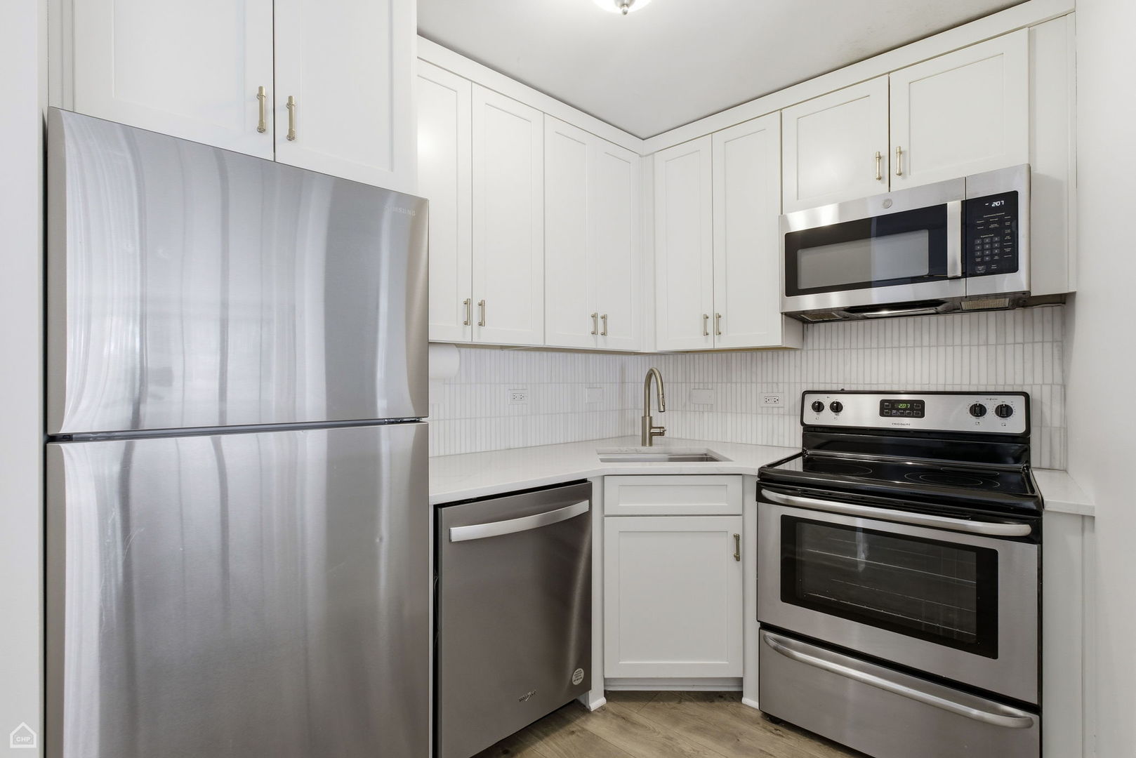 2930 North Sheridan Road, Unit 302 Chicago, IL 60657 - Photo 6 of 14 a kitchen with stainless steel appliances white cabinets white stove and a microwave