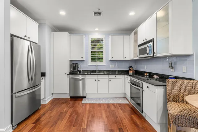 a kitchen with granite countertop stainless steel appliances a sink and a refrigerator