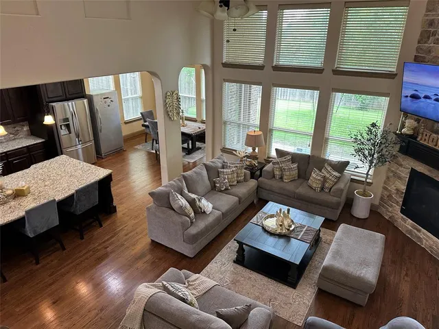 a living room with furniture a large window and wooden floor