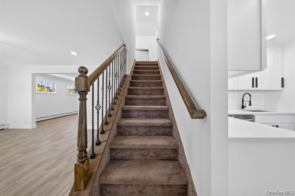 84 Cornflower Road Levittown, NY 11756 - Photo 13 of 17 Carpeted staircase with wrought iron balusters and wood handrail