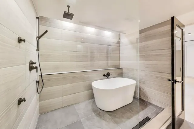 a view of an empty room with wooden floor and kitchen view
