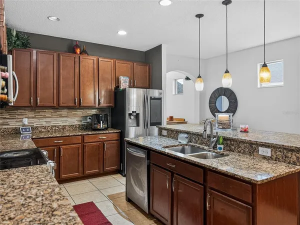 a kitchen with stainless steel appliances granite countertop sink stove refrigerator and cabinets