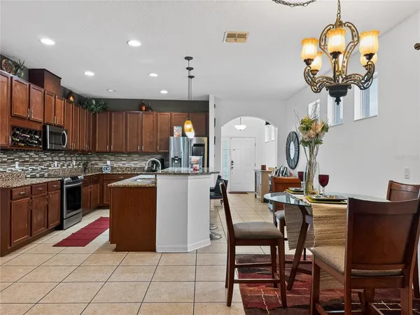 a kitchen with stainless steel appliances granite countertop a stove top oven a sink a dining table and chairs