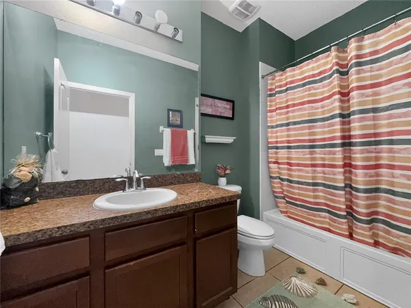 a bathroom with a granite countertop sink a toilet a mirror and shower curtain