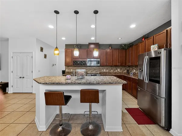 a kitchen with kitchen island granite countertop wooden cabinets and a refrigerator