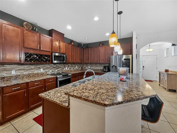 a kitchen with kitchen island granite countertop a sink a counter top space appliances and cabinets