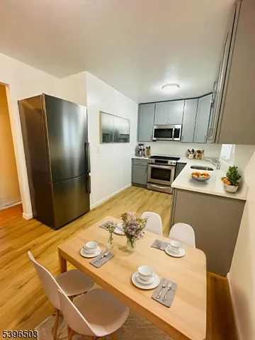 a kitchen with stainless steel appliances granite countertop a refrigerator a stove a sink a dining table and chairs with wooden floor