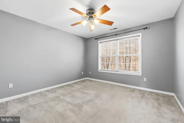 an empty room with windows and chandelier fan