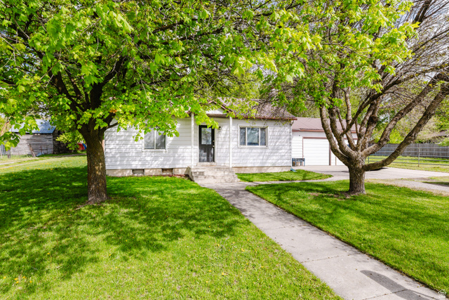 244 North 600 West Logan, UT 84321 - Photo 3 of 30 Ranch-style residence featuring white siding, a dark entry door, and a concrete pathway