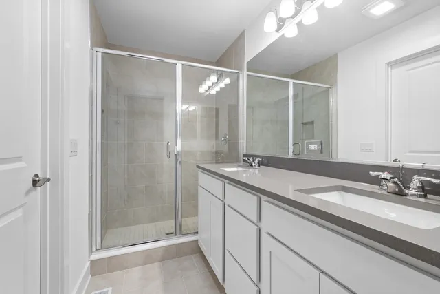 a bathroom with a double vanity sink mirror and shower