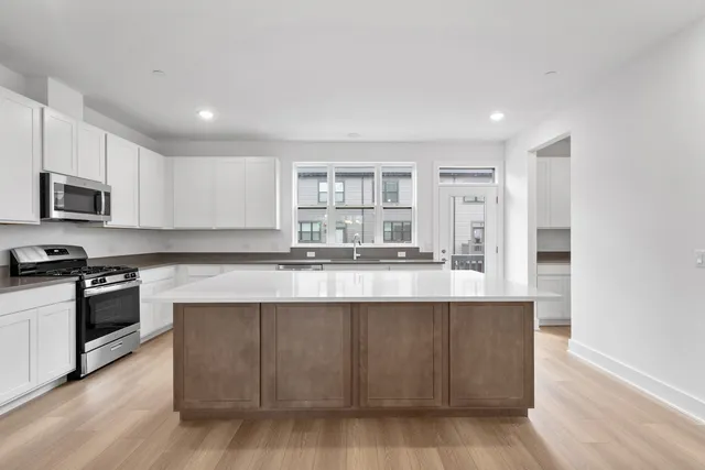 a kitchen with stainless steel appliances granite countertop a stove a sink and a microwave