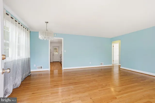 a view of an empty room with window and wooden floor