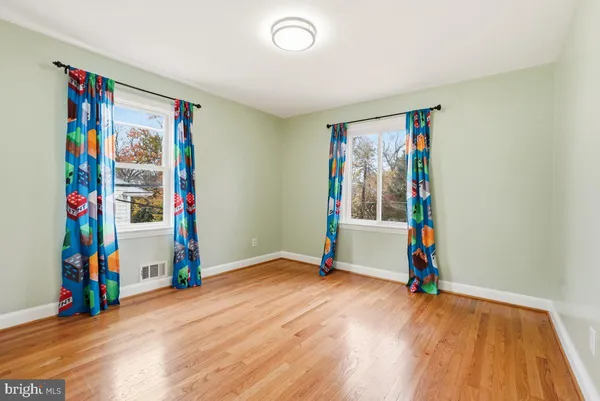 a view of an empty room with wooden floor and windows