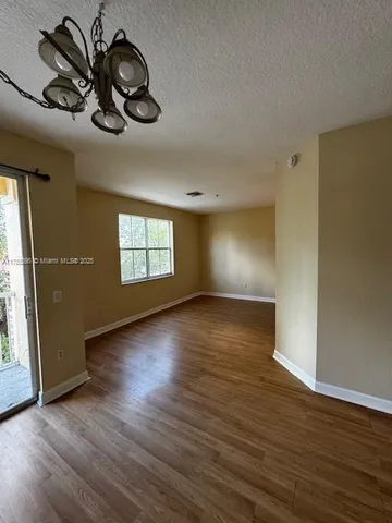 an empty room with wooden floor chandelier fan and windows