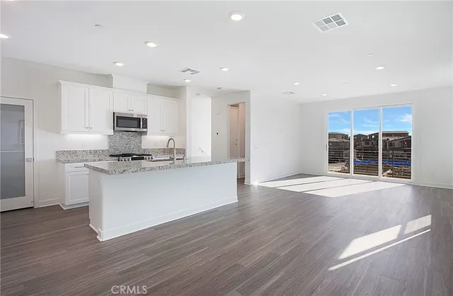a large kitchen with kitchen island a sink wooden floor and stainless steel appliances
