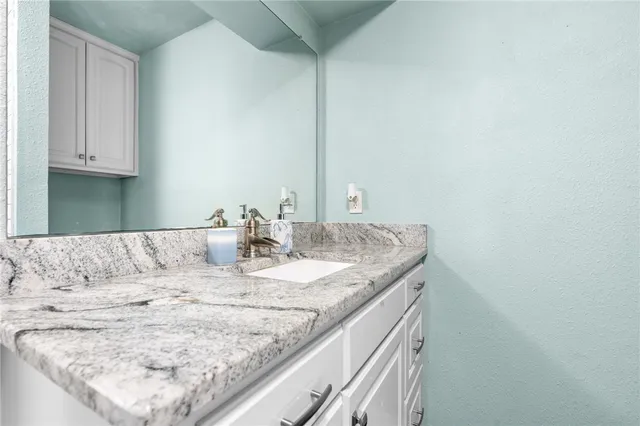 a bathroom with a granite countertop sink and a mirror