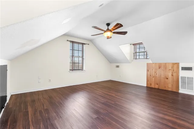 an empty room with wooden floor chandelier fan and windows