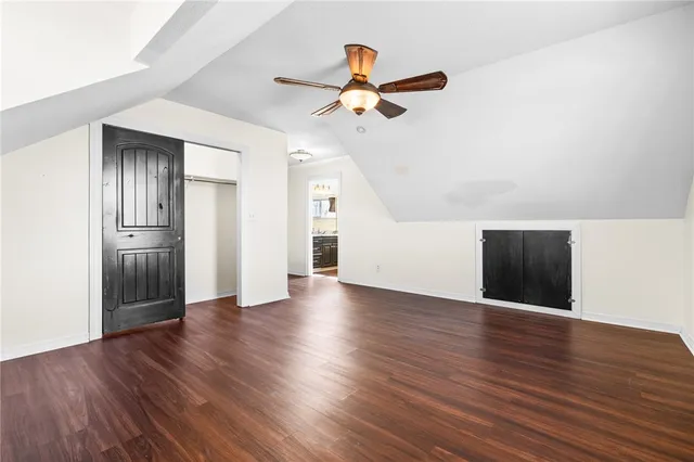 a view of an empty room with wooden floor and a ceiling fan