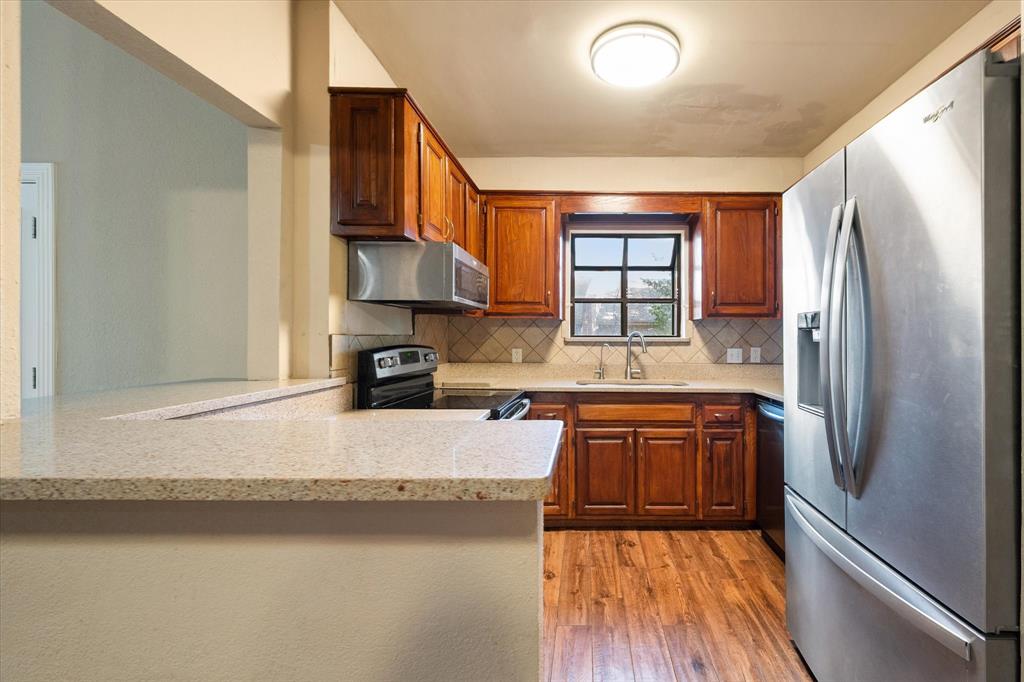 2312 Perkins Road Arlington, TX 76016 - Photo 18 of 37 a kitchen with stainless steel appliances granite countertop a refrigerator a sink dishwasher a stove and white countertops with wooden floor