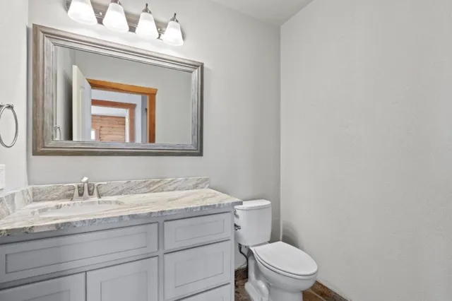 a bathroom with a granite countertop toilet a sink and mirror