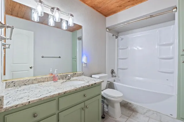 a bathroom with a granite countertop sink a toilet and shower