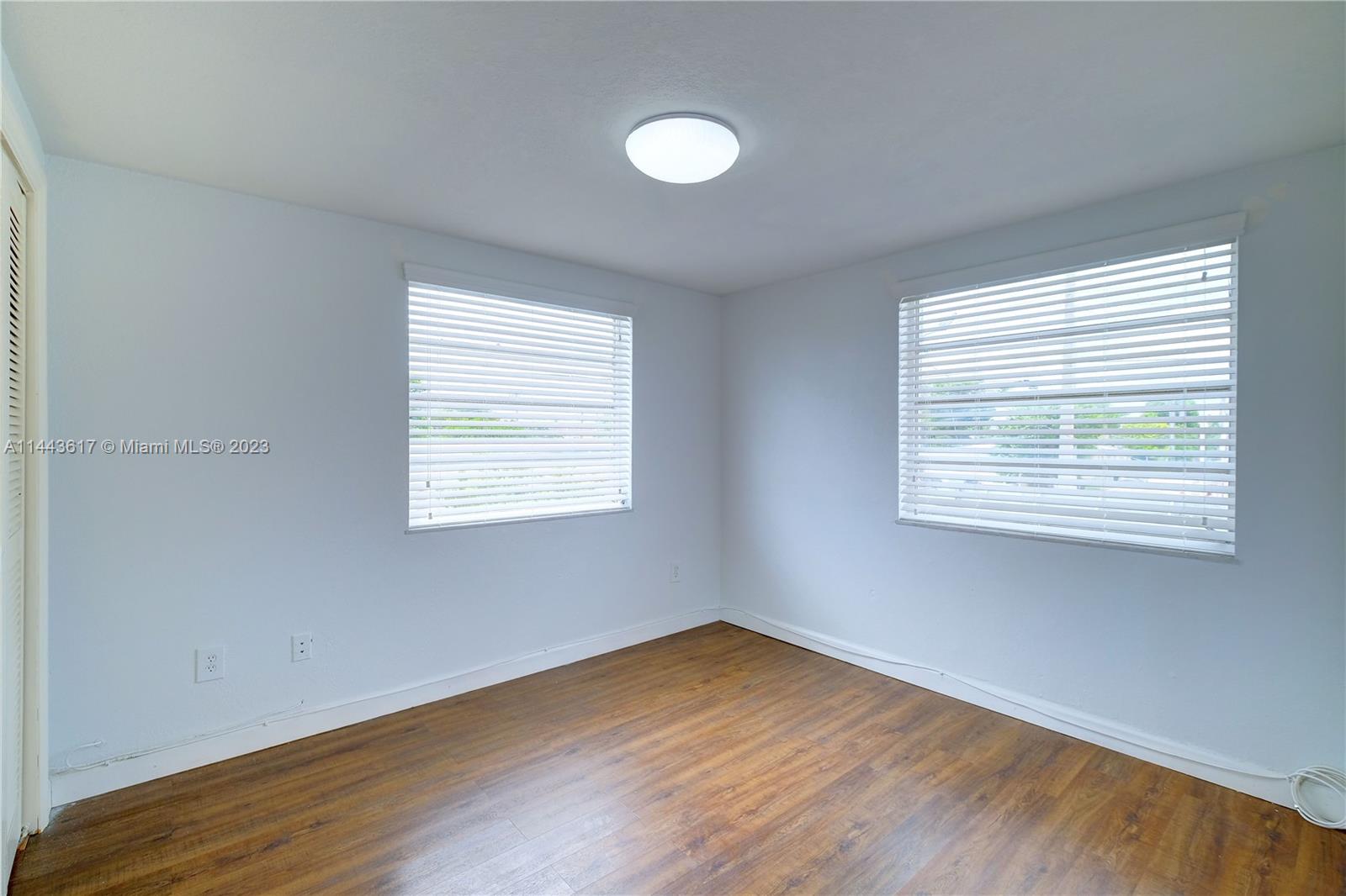 4640 Northwest 7th Street, Unit TOP Miami, FL 33126 - Photo 11 of 23 a view of an empty room with wooden floor and a window