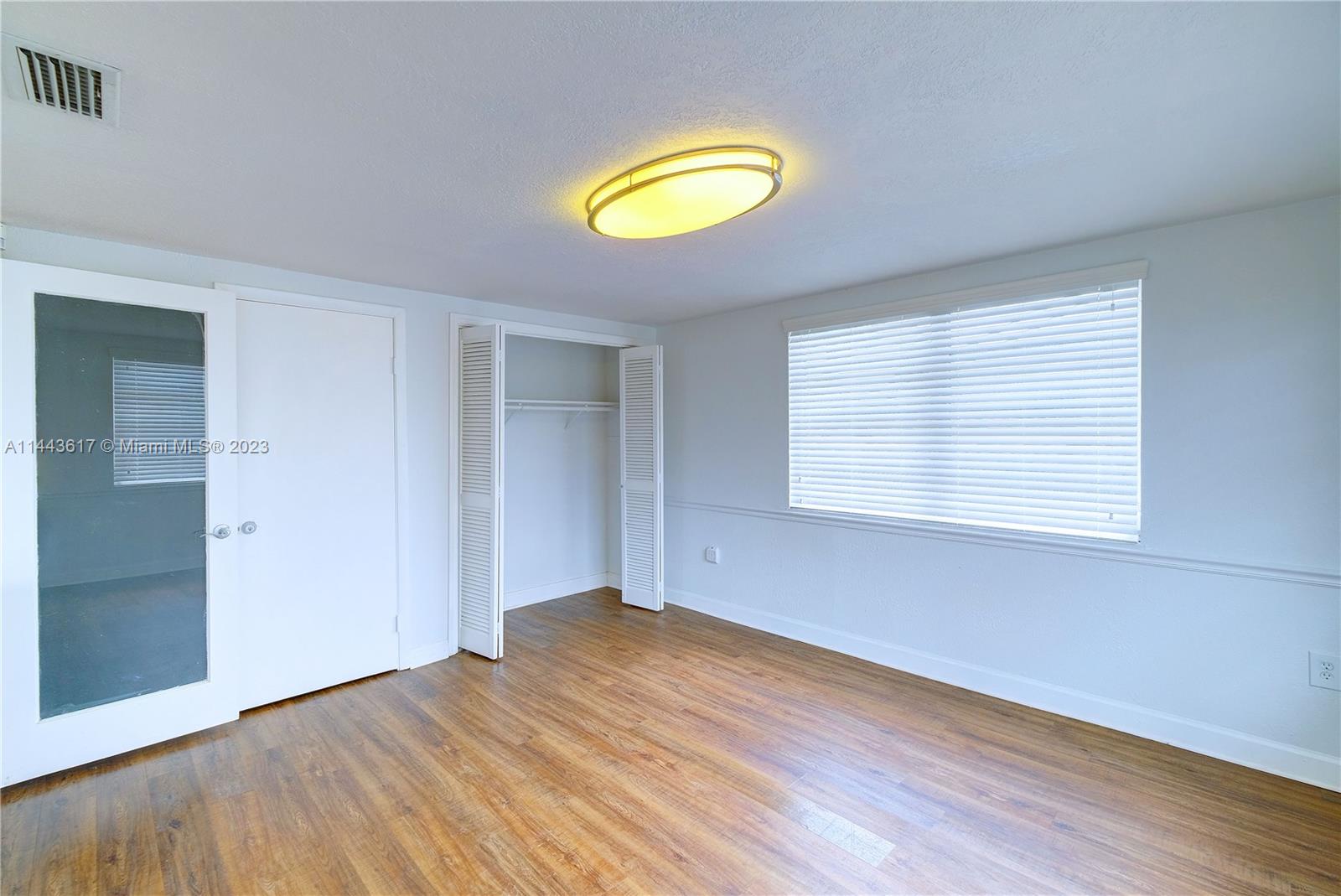 4640 Northwest 7th Street, Unit TOP Miami, FL 33126 - Photo 17 of 23 an empty room with wooden floor and windows