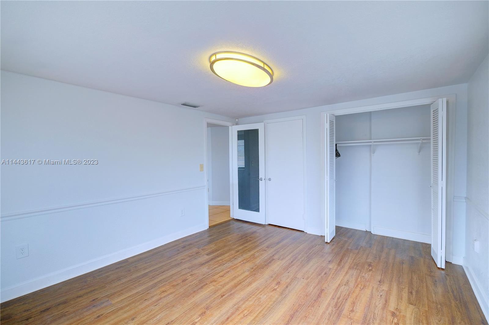 4640 Northwest 7th Street, Unit TOP Miami, FL 33126 - Photo 18 of 23 an empty room with wooden floor and window