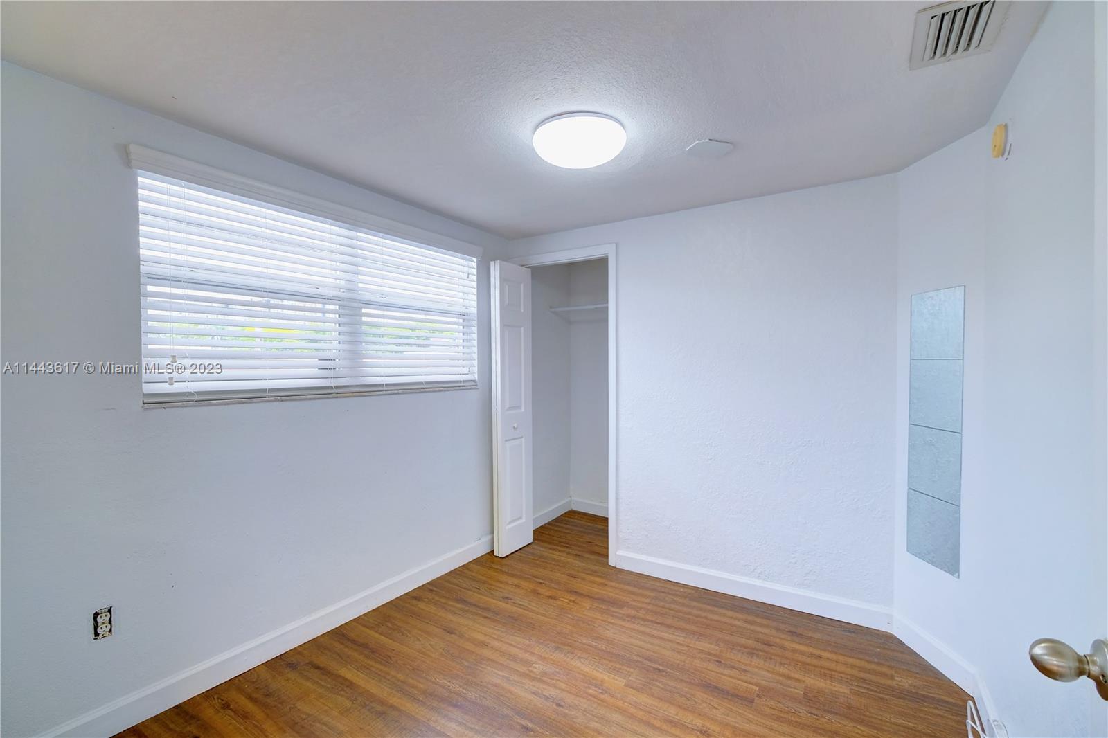 4640 Northwest 7th Street, Unit TOP Miami, FL 33126 - Photo 6 of 23 a view of an empty room with wooden floor and a window