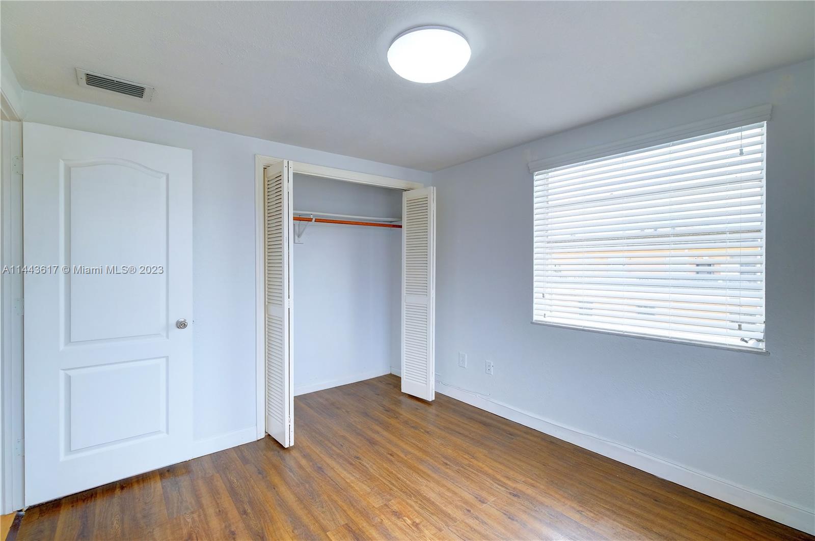 4640 Northwest 7th Street, Unit TOP Miami, FL 33126 - Photo 10 of 23 a view of an empty room with wooden floor and a window