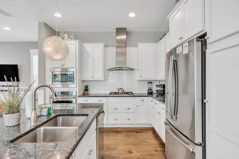 a kitchen with stainless steel appliances granite countertop a sink refrigerator and cabinets