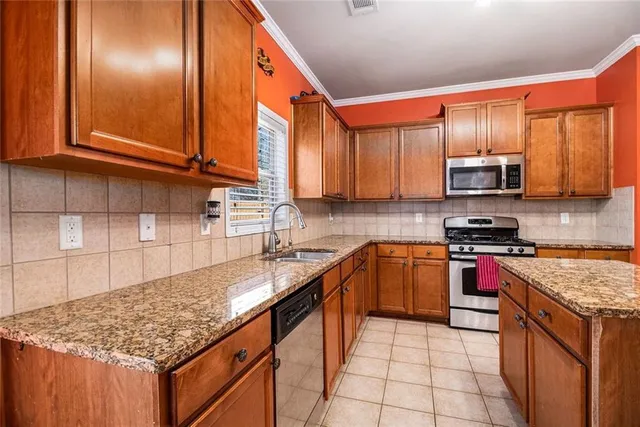 a kitchen with stainless steel appliances granite countertop a stove a sink and a microwave