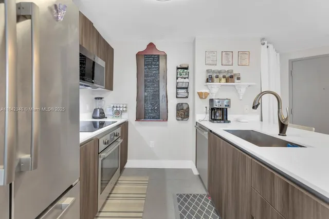 a kitchen with stainless steel appliances granite countertop a sink and a refrigerator