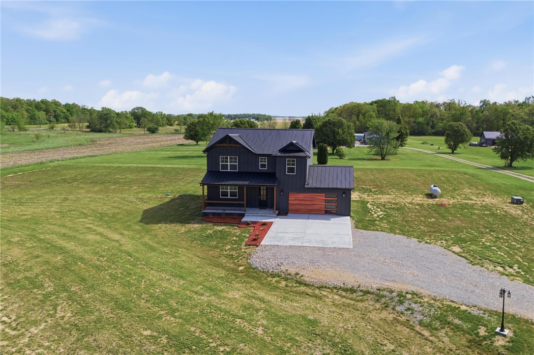 3509 South State Rte 72 Sabina, OH 45169 - Photo 36 of 44 Modern farmhouse with a dark exterior sits amidst a vast green landscape, offering serene rural living.
