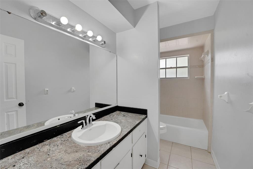 404 Lake Ned Road Winter Haven, FL 33884 - Photo 11 of 18 a bathroom with a granite countertop sink a large mirror and a bathtub