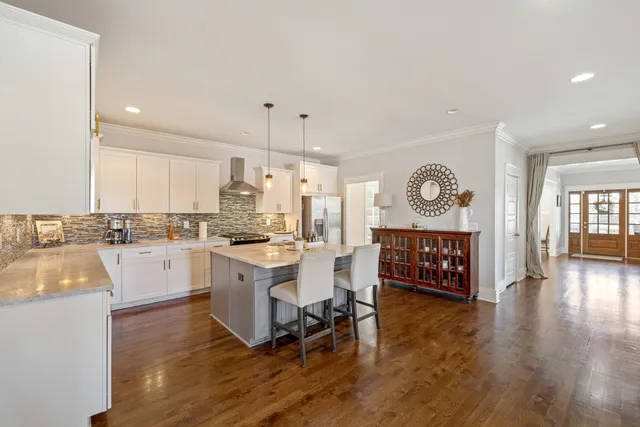 a large white kitchen with wooden floor and a refrigerator