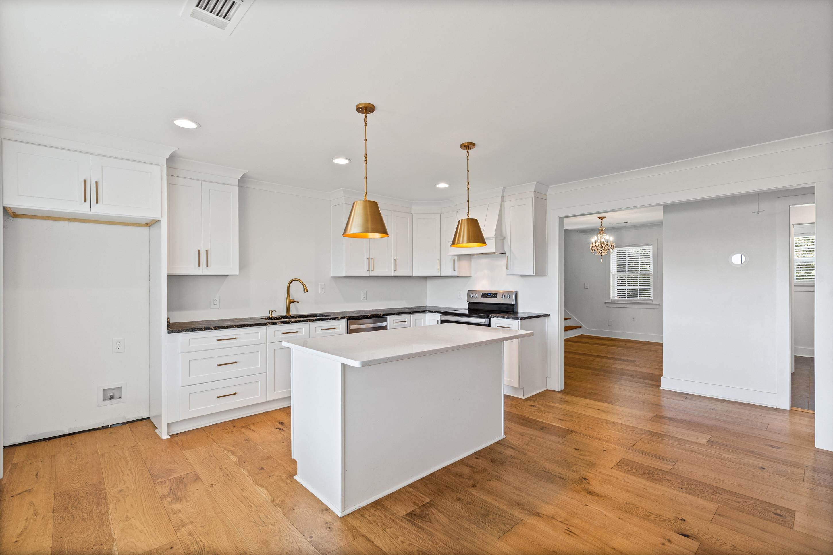 620 Diffee Road Moscow, TN 38057 - Photo 5 of 25 Modern kitchen featuring white cabinetry, a central island with white countertop, dark countertops, wood flooring, and brass pendant lighting
