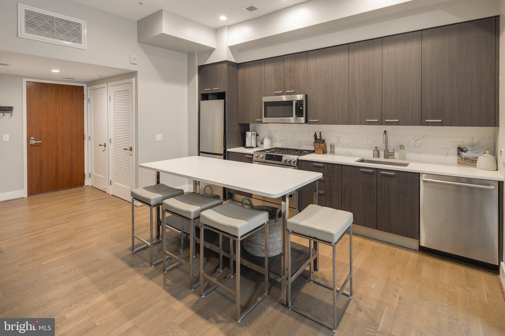 525 Southwest Water Street Southwest, Unit 404 Washington, DC 20024 - Photo 5 of 82 a dining hall with stainless steel appliances granite countertop a sink a stove a dining table and chairs