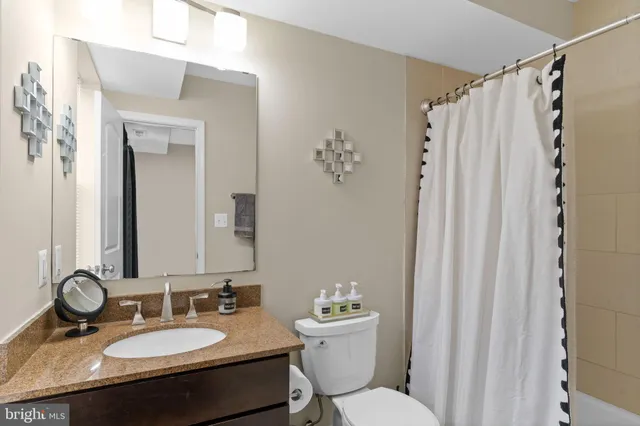 a bathroom with a granite countertop sink toilet a mirror a vanity and shower