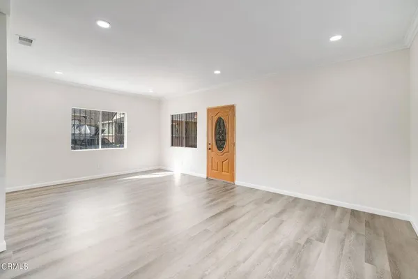 a view of an empty room with a window and wooden floor