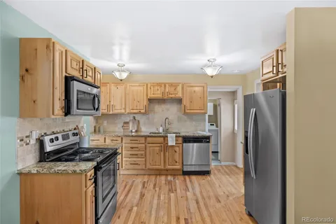 a kitchen with stainless steel appliances granite countertop a refrigerator a stove top oven a sink and dishwasher
