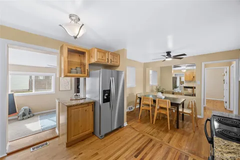 a kitchen with stainless steel appliances a dining table chairs refrigerator and sink