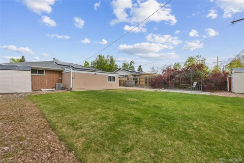 a backyard of a house with plants and large tree