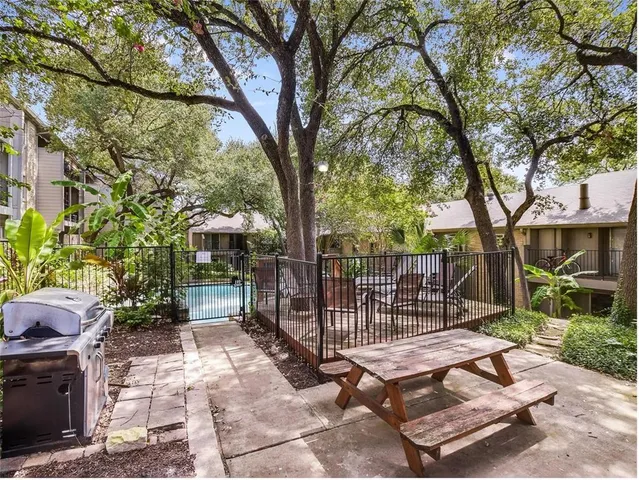 a backyard of a house with plants and large tree